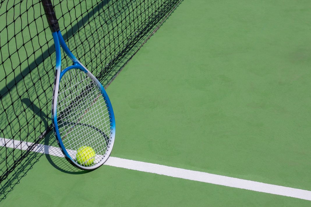 Rakieta tenisowa i piłka oparta od siatkę