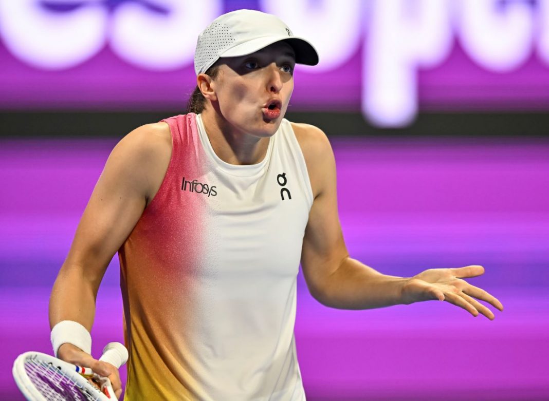 Iga Świątek rozkładająca ręce na korcie.