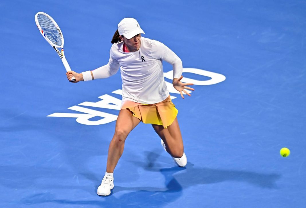 Iga Świątek odbijająca piłkę na korcie.