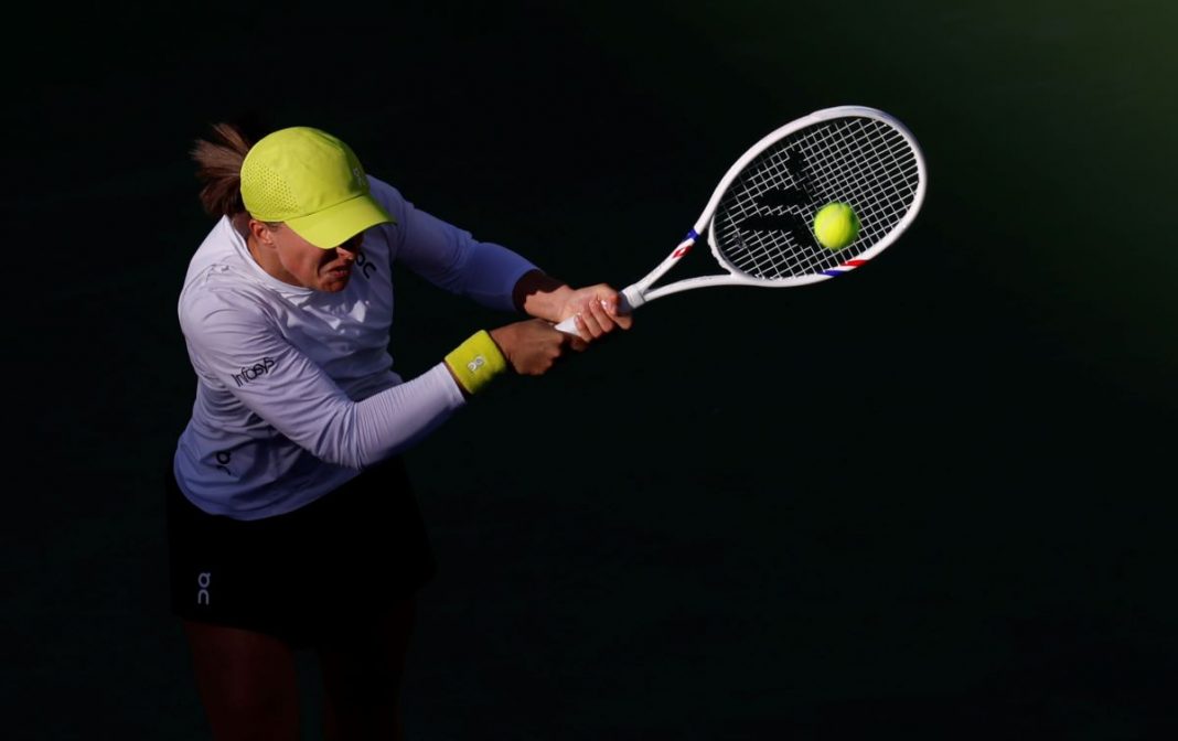 Iga Świątek odbijająca piłkę rakietą.