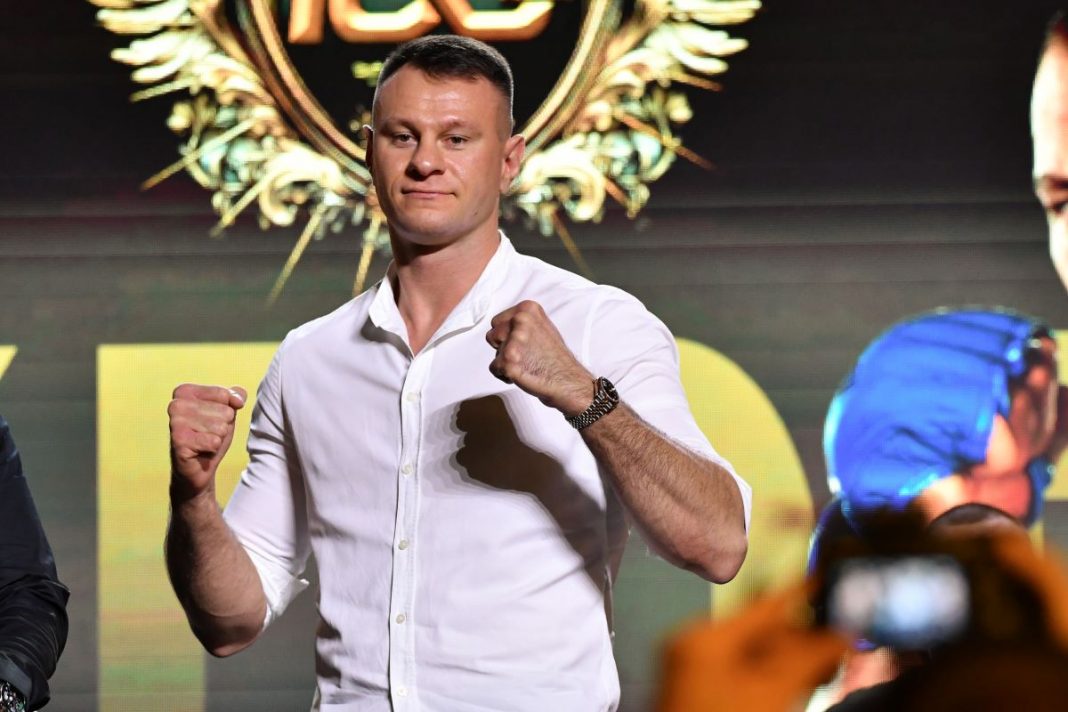 Arkadiusz Wrzosek pozujący z podniesionymi pięściami.