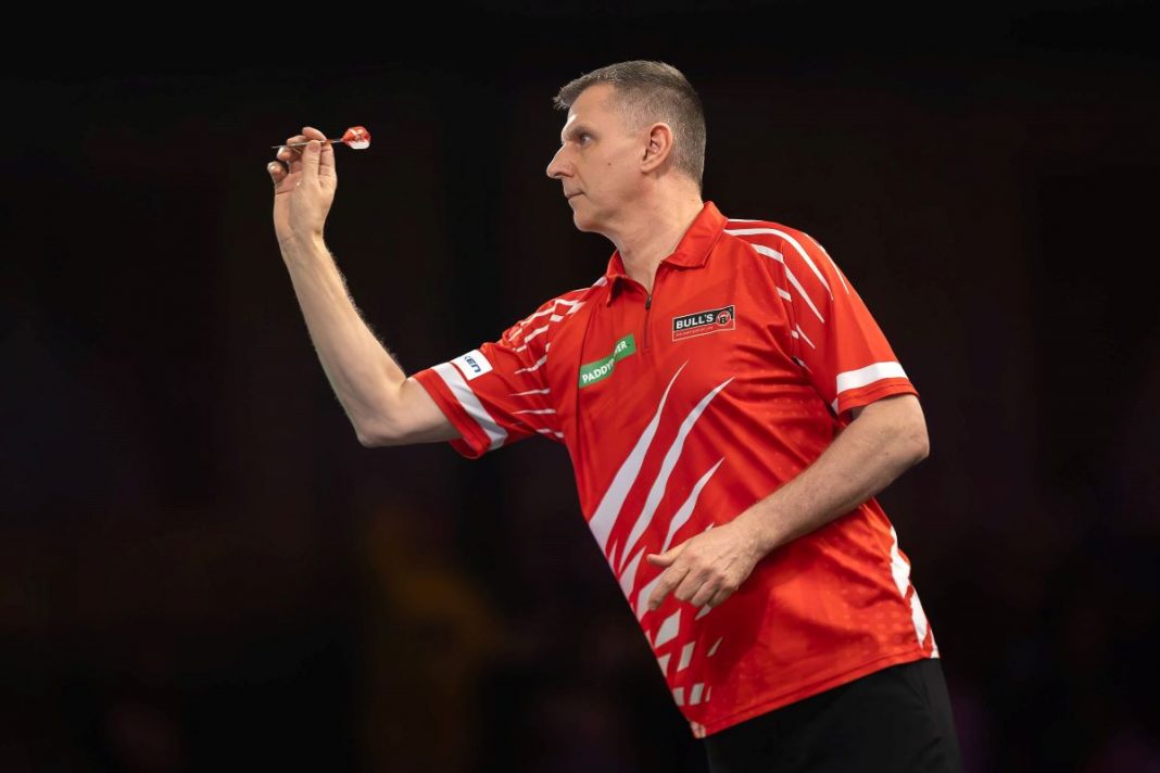 Krzysztof Ratajski w trakcie gry w darta.