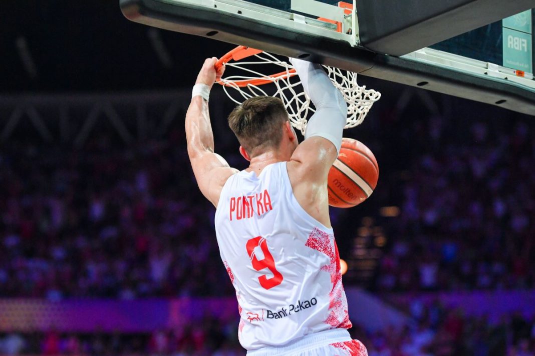 Mateusz Ponitka wykonujący wsad do kosza.